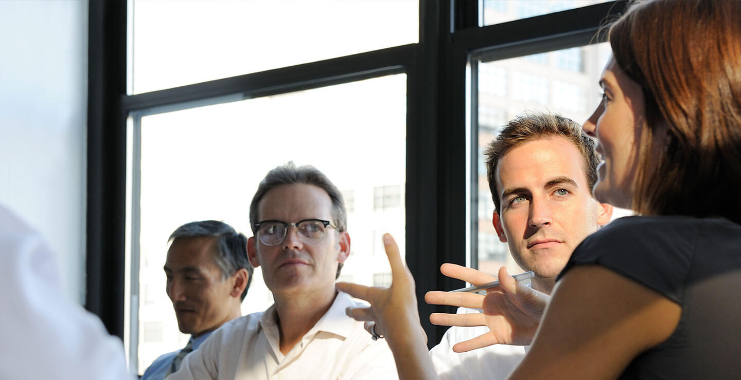 A shot of businessmen and women having a meeting in an office in late afternoon