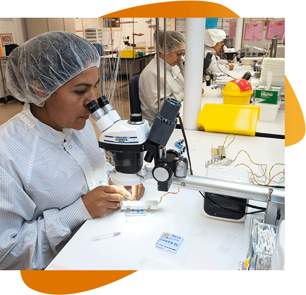 A picture of three female scientists in a row at microscopes soldering